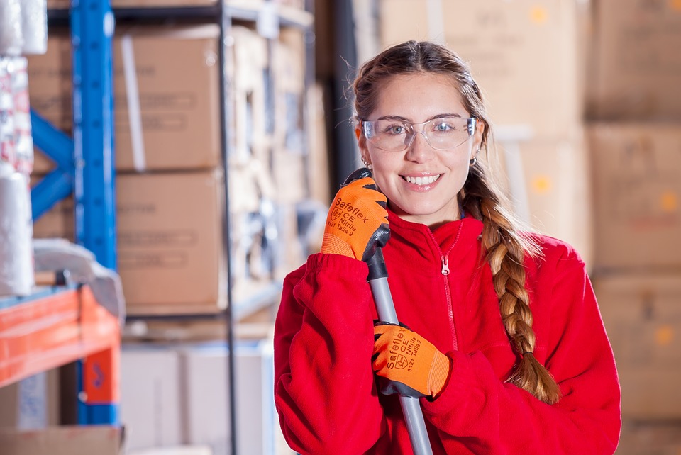 girl holding broom in warehouse